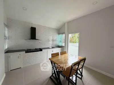 Modern kitchen with sleek design and open layout, featuring a wooden dining table and gas stove.
