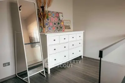 Stylish modern bedroom corner with white dresser and floor mirror, perfect for chic living.