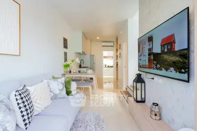Modern living room with stylish decor and open kitchen layout, featuring a cozy sofa and large wall-mounted TV.