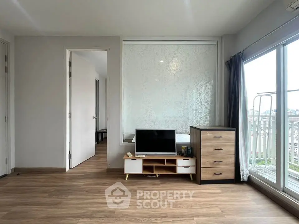 Spacious living room with wooden flooring and large windows offering city views.