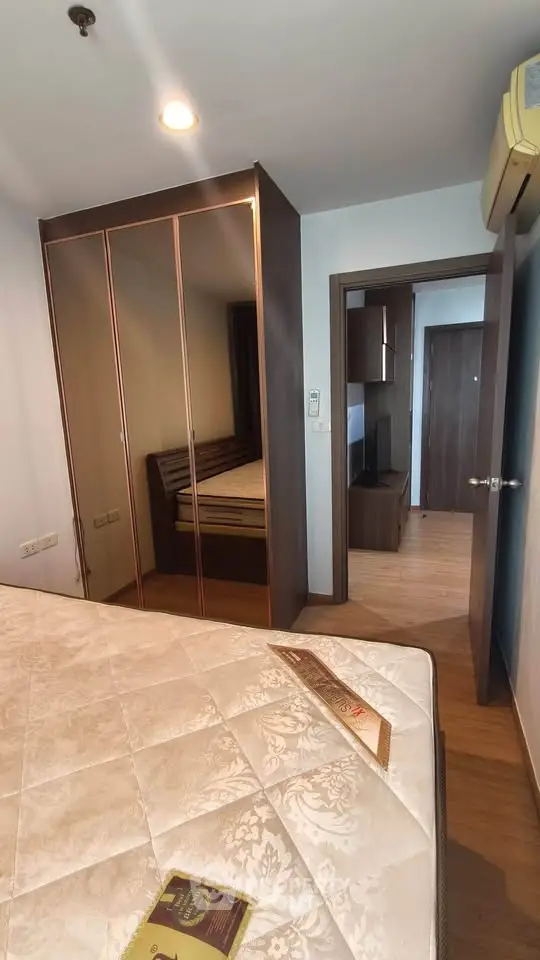 Cozy bedroom with wooden flooring and mirrored wardrobe in modern apartment