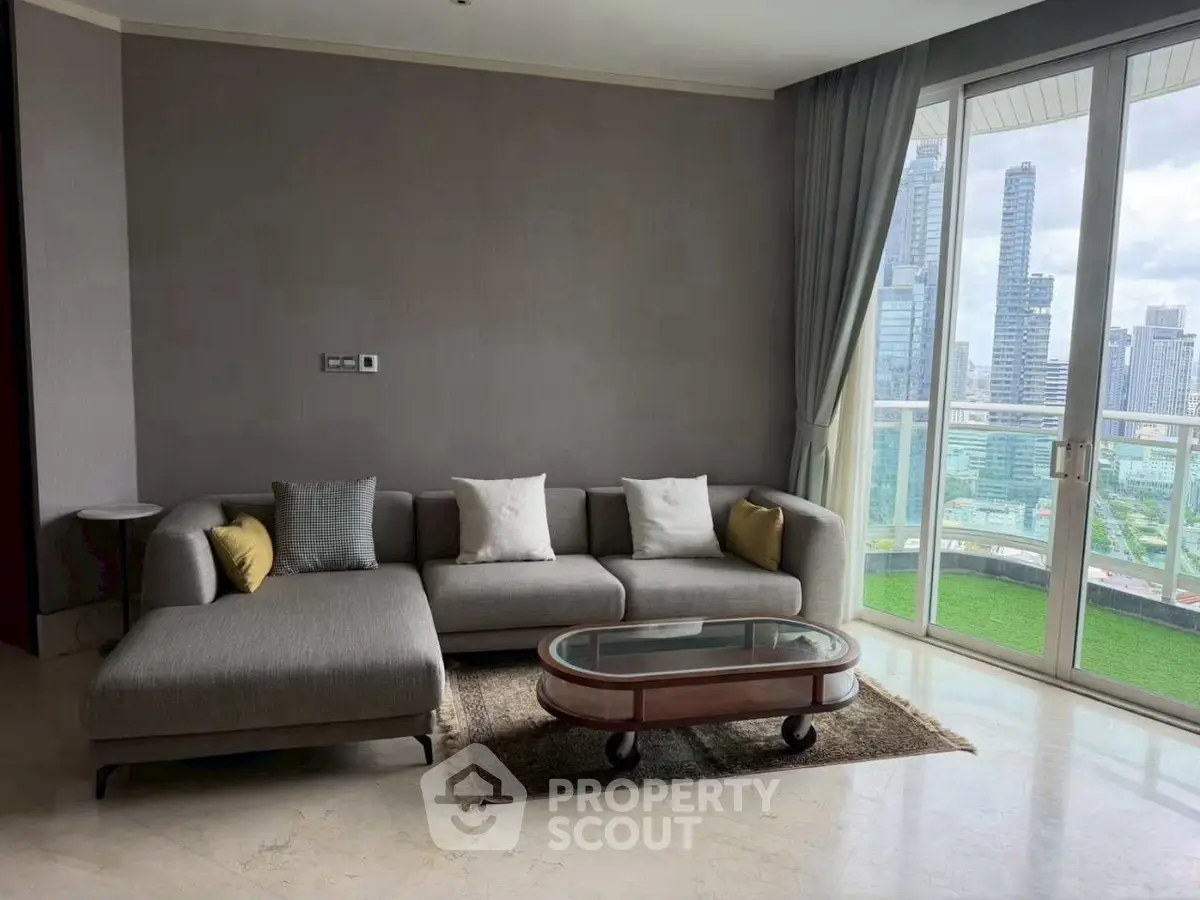 Modern living room with city view, featuring a stylish gray sofa and glass coffee table.