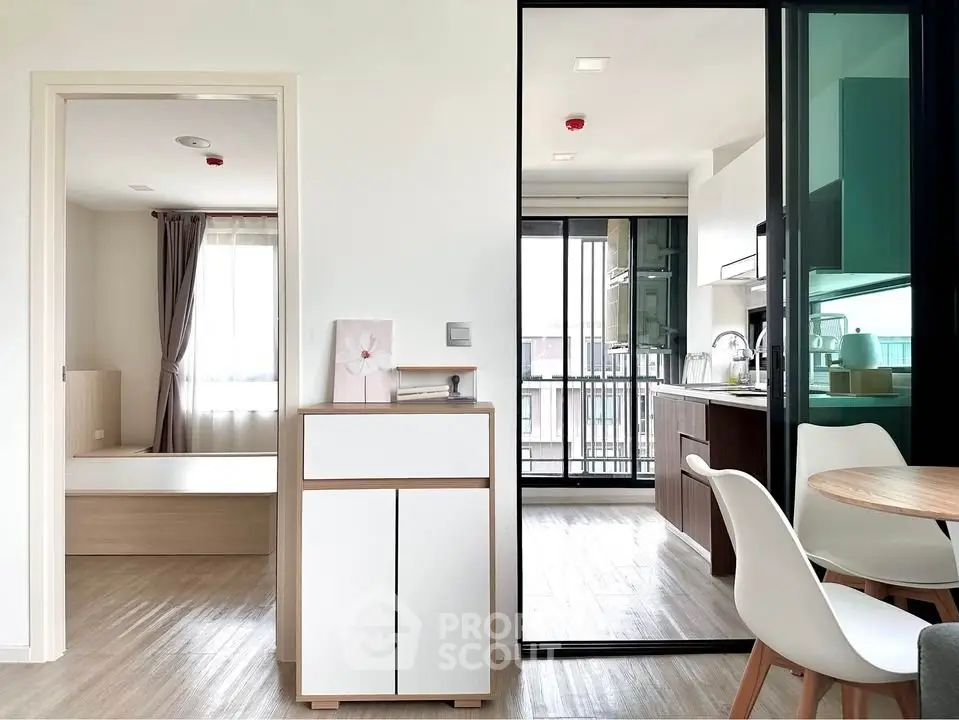 Modern apartment interior with open kitchen and dining area, featuring sleek furniture and natural light.