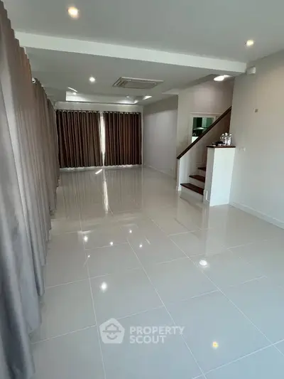 Spacious modern living room with glossy tile flooring and elegant curtains.