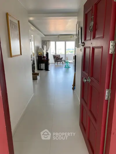 Spacious apartment entrance leading to a bright living area with large windows and modern decor.