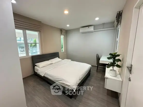 Modern bedroom with sleek design, featuring a comfortable bed and workspace, ideal for urban living.