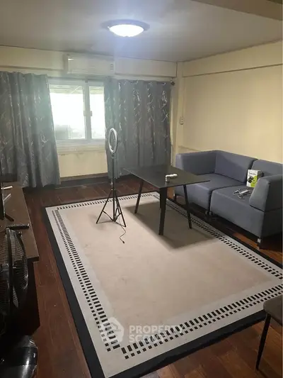 Spacious living room with modern decor and natural light, featuring a stylish rug and comfortable seating.