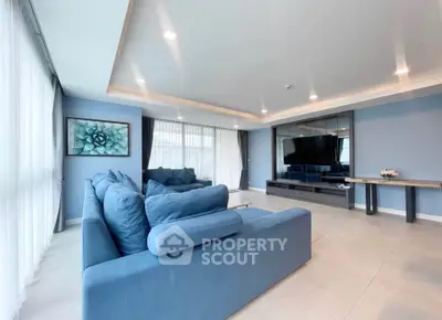 Spacious modern living room with blue sofas and large TV, perfect for relaxation.