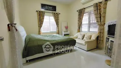 Spacious bedroom with cozy seating and natural light, perfect for relaxation.