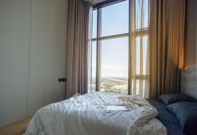 Luxurious bedroom with floor-to-ceiling windows offering stunning city views, perfect for urban living.