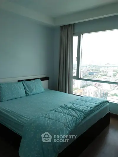 Bright bedroom with large window offering stunning city view, featuring cozy blue bedding and modern decor.