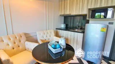 Chic studio apartment with a sleek kitchenette featuring modern appliances, a cozy sitting area with a plush sofa, and a compact dining space, all bathed in natural light.