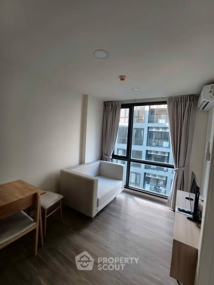 Modern living room with natural light and city view, featuring a cozy sofa and dining area.