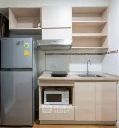 Modern compact kitchen with fridge, microwave, and ample storage space.