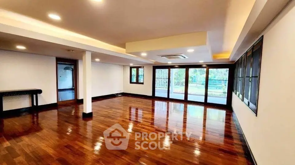 Spacious hardwood floor living room with large windows and abundant natural light.