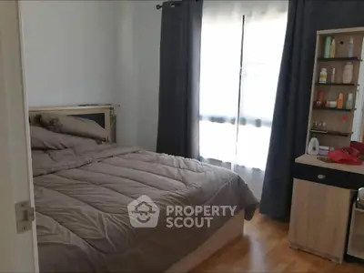 Cozy bedroom with natural light, wooden flooring, and modern furnishings.