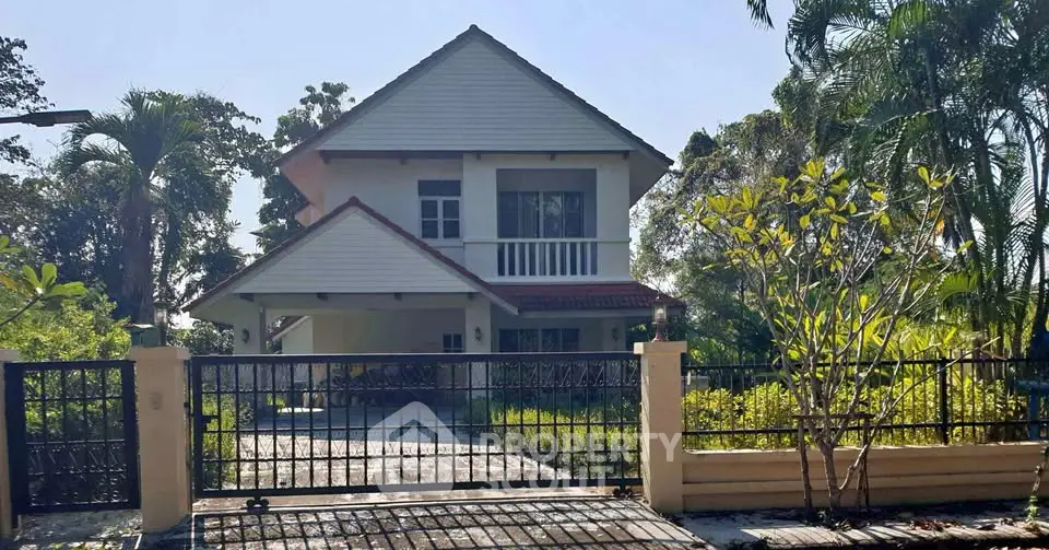 Charming two-story house with lush garden and gated entrance in serene neighborhood.