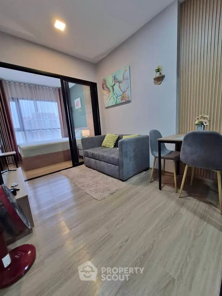 Modern living room with cozy sofa, dining area, and view into stylish bedroom.