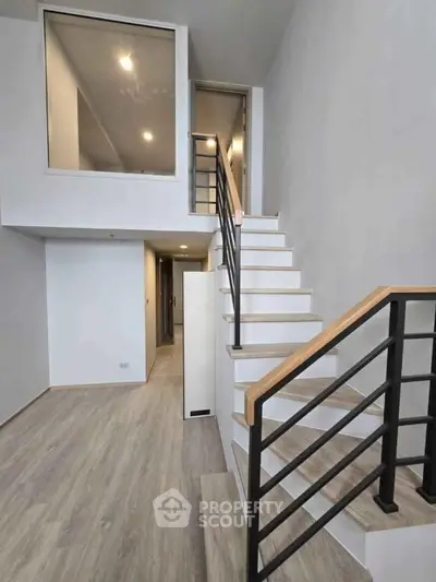 Modern duplex interior with sleek staircase and large window