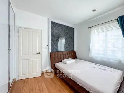 Modern bedroom with sleek design and natural light, featuring a stylish bed and wooden flooring.
