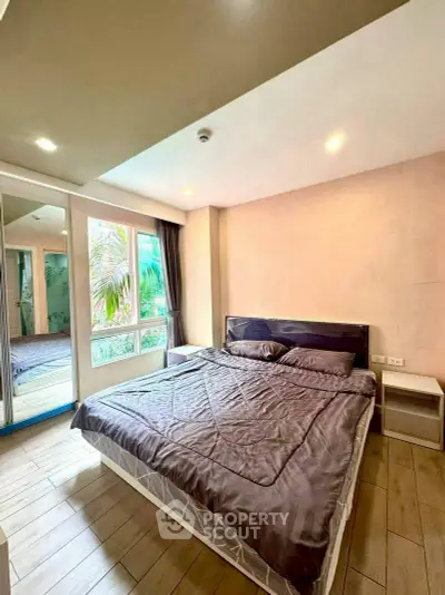 Spacious bedroom with large window and modern decor in a serene setting.