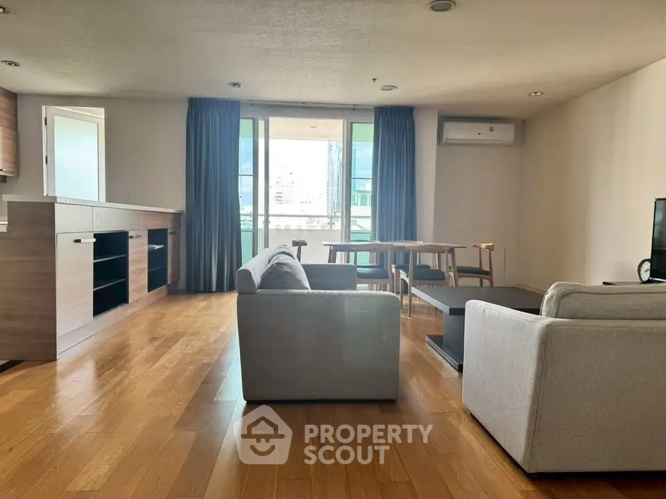 Spacious modern living room with wooden flooring and open kitchen layout.