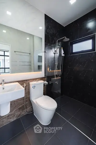 Modern bathroom with sleek black tiles and glass shower enclosure