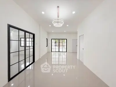 Spacious modern living room with sleek tile flooring and stylish lighting, featuring large windows for natural light.