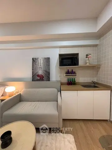 Modern living room with cozy sofa and compact kitchenette in stylish apartment.