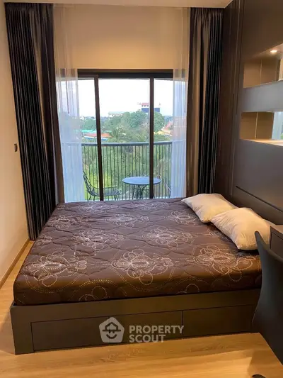 Cozy bedroom with a view, featuring a comfortable bed and access to a private balcony overlooking greenery.