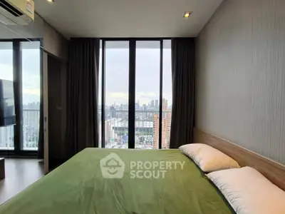 Modern bedroom with large windows offering stunning city views, featuring a cozy bed and elegant decor.