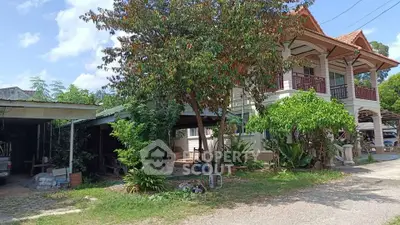 Charming two-story house with lush garden and carport in a serene neighborhood.