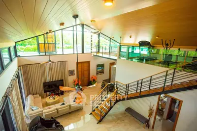 Stunning modern living room with high ceilings, large windows, and elegant staircase in a luxurious home.