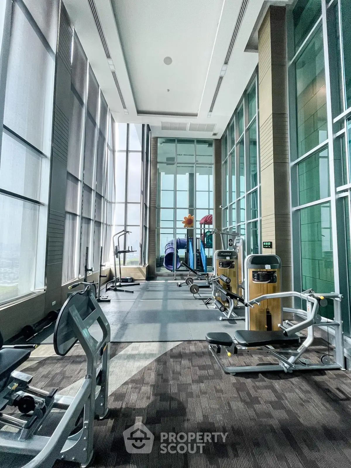 Spacious modern gym with floor-to-ceiling windows and state-of-the-art equipment.