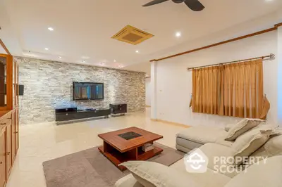 Spacious living room with elegant stone accent wall, modern furniture, and warm lighting, perfect for family gatherings and relaxation.