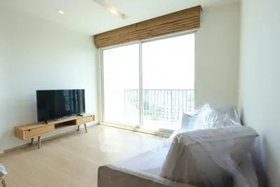 Modern living room with large window and balcony view, featuring a sleek TV stand and cozy seating area.