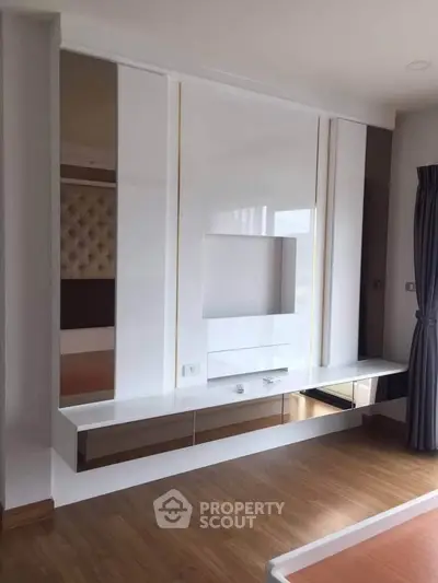 Modern living room with sleek built-in entertainment unit and wooden flooring.