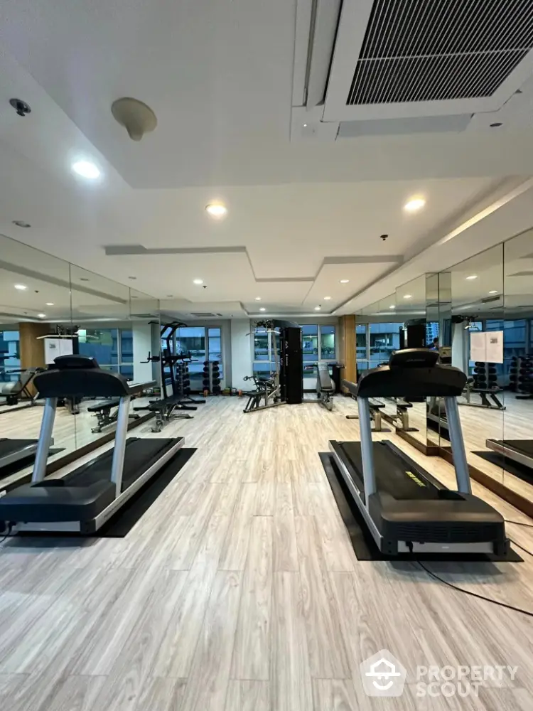 Modern gym with treadmills and mirrored walls in luxury apartment building