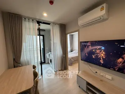 Modern apartment interior with open living area, dining table, and wall-mounted TV, leading to a cozy bedroom.