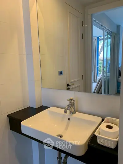 Modern bathroom with sleek sink and large mirror reflecting a bright interior view.
