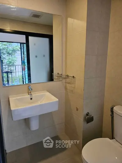 Modern bathroom with sleek fixtures and outdoor view through frosted window.