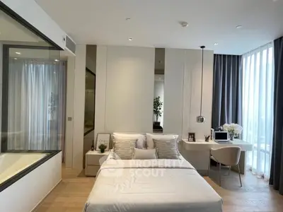 Modern bedroom with elegant decor, large window, and cozy workspace, perfect for urban living.