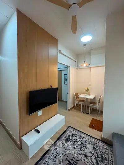 Modern apartment interior with stylish living area and dining space, featuring wood paneling and ceiling fan.