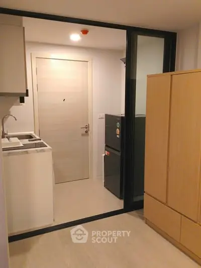 Compact kitchen area with modern appliances and sleek cabinetry in a cozy apartment.