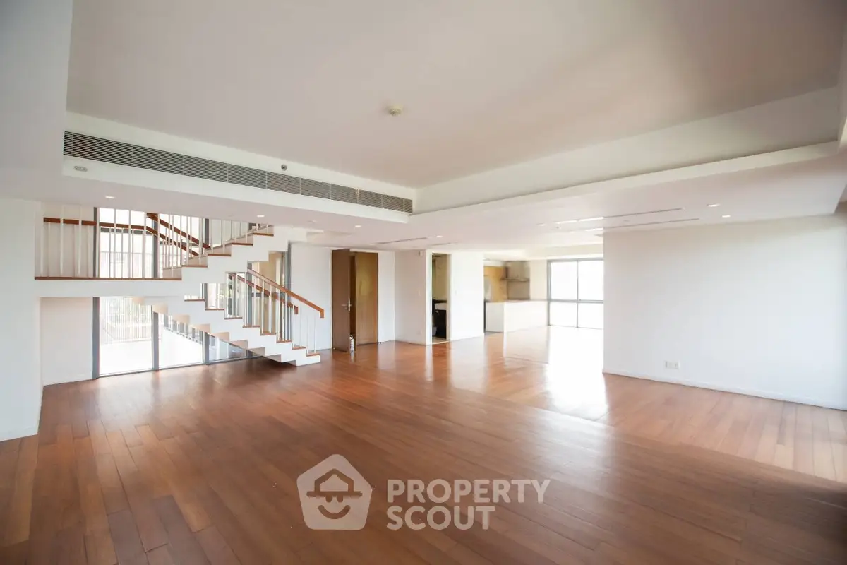 Spacious modern living room with wooden flooring and open staircase in luxury apartment