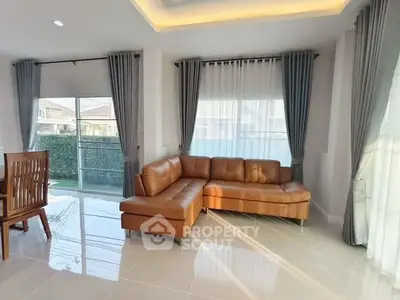 Spacious living room with modern leather sofa and large windows offering natural light.