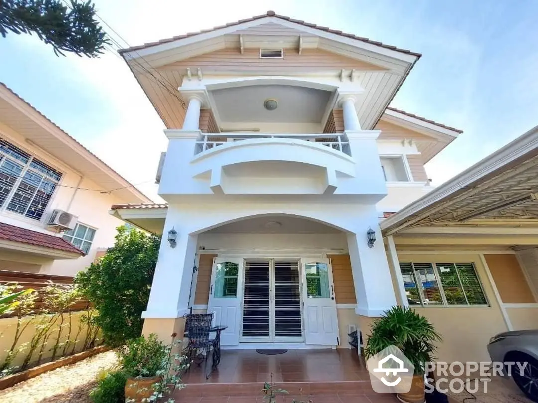 Charming two-story home with a welcoming porch, elegant balcony, and a lush garden, perfect for family living in a serene neighborhood.