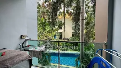 Tropical balcony view overlooking a serene pool surrounded by lush greenery.