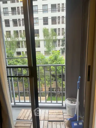 Charming balcony with wooden flooring and lush green view, perfect for relaxation.