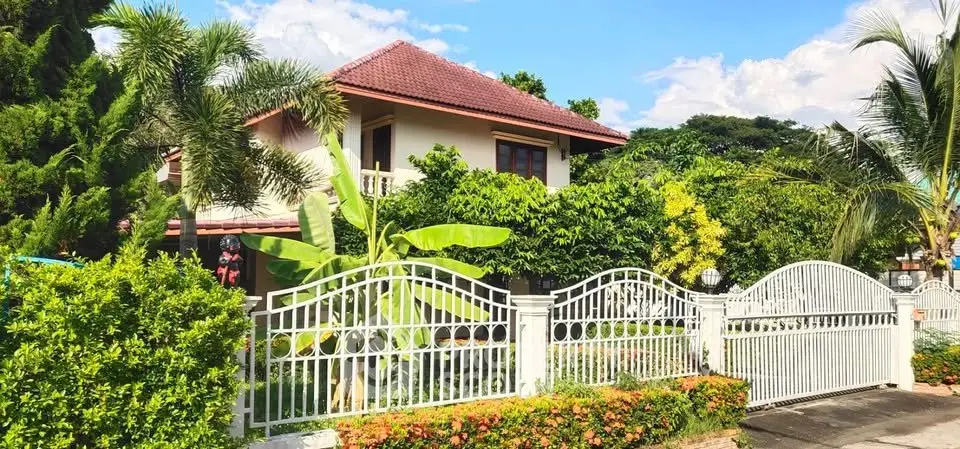 Charming tropical villa with lush garden and elegant white gate